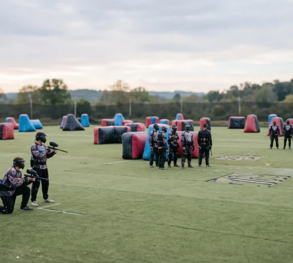 Deux capitaines d'equipe de paintball face a face sur un terrain exterieur, symbolisant le choix entre les formats 3v3, 5v5 et 7v7